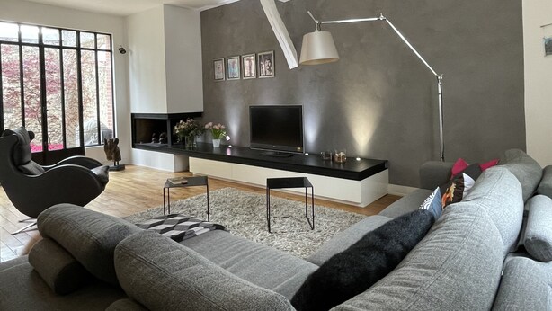 A modern living room with a large window, a flat-screen TV, a sofa, a coffee table, and a floor lamp. - The charm of a family home in Tours (Tours)