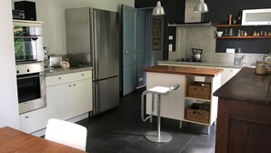 A modern kitchen with stainless steel appliances, a wooden island, and a bar stool. - The charm of a family home in Tours (Tours)