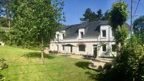A two-story building with a patio area, outdoor seating, and a well-maintained lawn. - Villa Mathilde, a 2-minute walk from the beach (Saint-Pierre-en-Port)