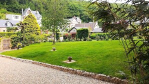 A well-maintained lawn with a gravel path, surrounded by lush greenery and houses. - Villa Mathilde, a 2-minute walk from the beach (Saint-Pierre-en-Port)
