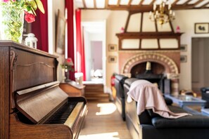 A grand piano in a cozy living room with a fireplace and a sofa.