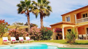 A pool with lounge chairs, a barbecue area, and a two-story building with a balcony. - Quiet villa Beach 10' walk Outdoor SPA Heated pool Boules court  (Saint-Cyr-Sur-Mer)