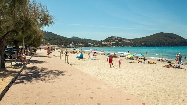 A beach with people sunbathing, walking, and swimming. There are umbrellas and beach chairs. - Quiet villa Beach 10' walk Outdoor SPA Heated pool Boules court  (Saint-Cyr-Sur-Mer)