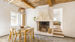 Un comedor con mesa y sillas de madera, chimenea y suelo estampado.