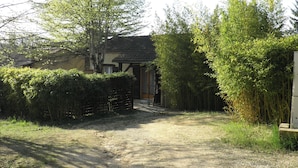 Una casa rurale con un sentiero sterrato che conduce all'ingresso, immersa nel verde e circondata da alberi.