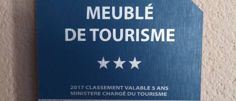 Une plaque bleue, ornée d’un texte et d’un logo, fixée à un mur à texture.