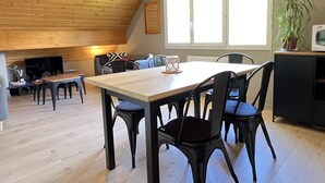 Un coin repas avec une table et des chaises en bois, un téléviseur et une cheminée.