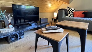 Un salon moderne avec un téléviseur à écran plat, une table basse, un canapé et une petite table d’appoint.