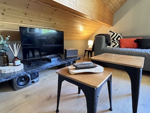 Ein modernes Wohnzimmer mit Flachbildfernseher, Couchtisch, Sofa und kleinen Beistelltisch.