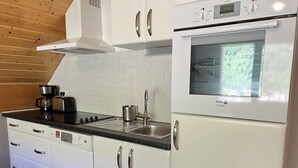 Une cuisine moderne avec des meubles blancs, un four encastré et une machine à café.