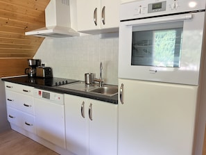 Eine moderne Küche mit weißen Schränken, einem eingebauten Backofen und einer Kaffeemaschine.