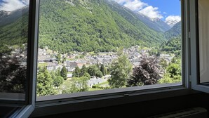 Un paysage de montagne avec une ville en contrebas, vu à travers une fenêtre.