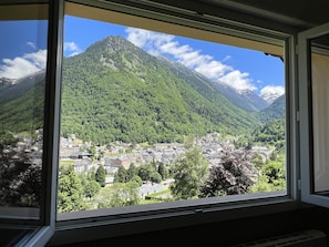 Eine Berglandschaft mit einer Stadt im Tal, wie durch ein Fenster betrachtet.