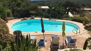 A swimming pool with lounge chairs and umbrellas, surrounded by greenery and a view of the sea. - Ground floor, 4p, swimming pool, air conditioning, mature garden, wide sea view near Fautéa beaches (Zonza)