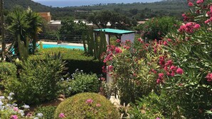 A pool surrounded by lush greenery and cacti, with a view of the sea and hills in the background. - Ground floor, 4p, swimming pool, air conditioning, mature garden, wide sea view near Fautéa beaches (Zonza)