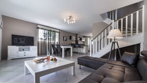 Ein modernes Wohnzimmer mit einer Couch, einem Esstisch und einem Fernseher.