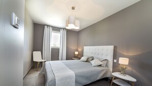Ein modernes Schlafzimmer mit einem großen Bett, Nachttischen und einem Fenster mit Vorhängen.