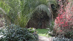 Ein Gartenweg, umgeben von üppigem Grün und blühenden Pflanzen.