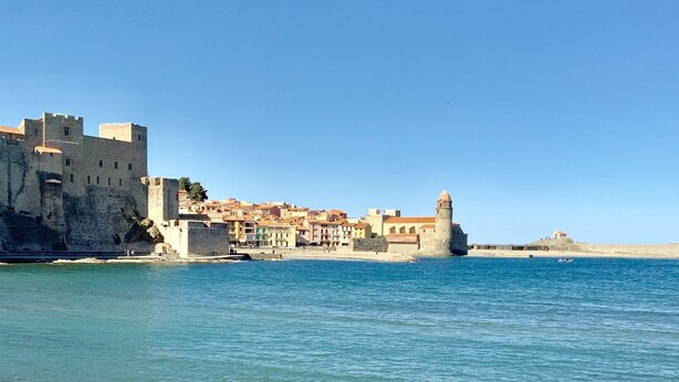 Eine Küstenstadt mit historischen Gebäuden und einer Festungsanlage am Meer.
