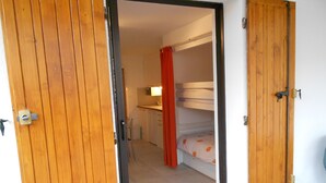 Ein Zimmer mit Etagenbett, einer kleinen Küchenzeile und einer Tür zu einem weiteren Raum.