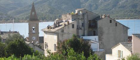 A coastal town with a prominent clock tower, terraced houses, and a backdrop of mountains.