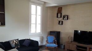 A living room with a sofa, a coffee table, a TV, and a window. - Bassin d'Arcachon - Beautiful house near the port of Cassy (Lanton)