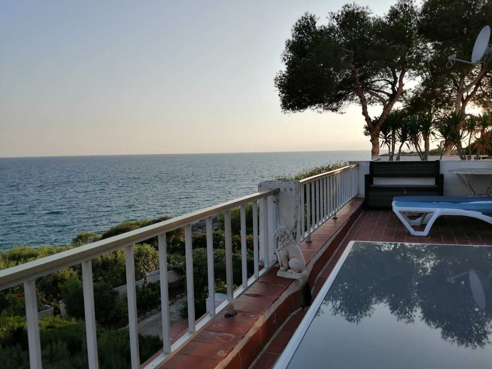 Een balkon met uitzicht op zee, een lounge stoel en een beeld.