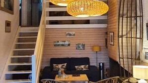 Ein modernes Interieur mit Treppe, einer Sofagarnitur, Korbstühlen und einer Pendelleuchte.