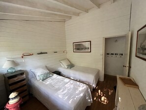 A room with two beds, a desk with a lamp, and a door leading to a bathroom.