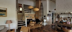 A cozy interior with a staircase, wicker furniture, and a wooden dining table.