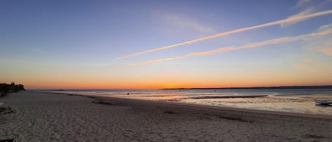 A beach with a clear sky and a sunset.