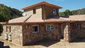 A stone house with a tiled roof, multiple windows, and a satellite dish.