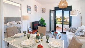 Ein modernes Wohnzimmer mit Essbereich, einer Couch, einem Fernseher und einem Balkon mit Blick.