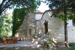 A stone building with a wooden door and steps leading up to it. There is a table and chairs outside the building. - Beautifully restored 18th-century mill on the river. (LIEU DIT RAURET)