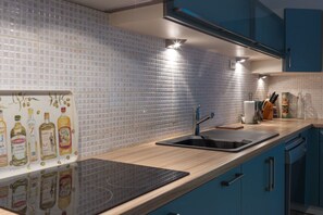 A modern kitchen with blue cabinets, a black sink, and a tiled backsplash. - Beautifully restored 18th-century mill on the river. (LIEU DIT RAURET)