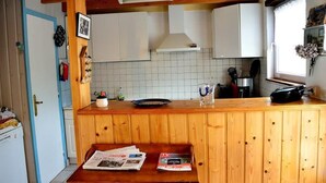 A compact kitchen with wooden cabinets, a tiled backsplash, and a small countertop. - House                         (Tréguennec)