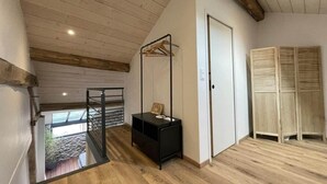 Una habitación con piso de madera, un mueble de almacenamiento negro, un perchero de madera y una puerta.