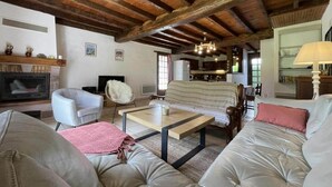 Un salón amplio con chimenea, sofás de cuero, una mesa de centro y una cocina al fondo.