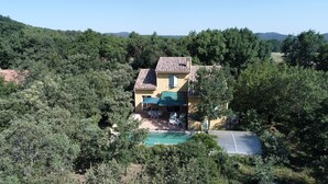 A house with a tiled roof, a swimming pool, and a patio area with outdoor furniture.