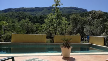 A swimming pool with a view of a forested mountain range.