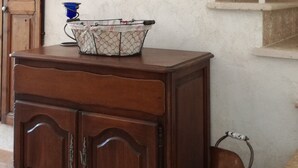 A wooden cabinet with drawers and a metal basket on top, positioned in front of a staircase with white railings and wooden steps.