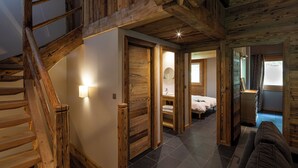 A wooden staircase leading to a bedroom with a bed, a bathroom with a mirror, and a small sitting area with a bench.