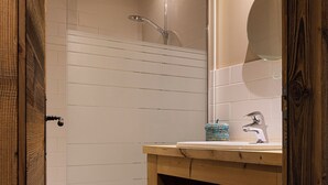 A bathroom with a wooden vanity, a mirror, and a shower enclosure.