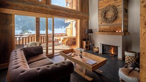 A cozy cabin interior with a fireplace, a sofa, and a dining table.