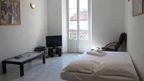 Habitació d'hotel amb un llit, una televisió sobre un prestatge, una taula petita i una cadira.