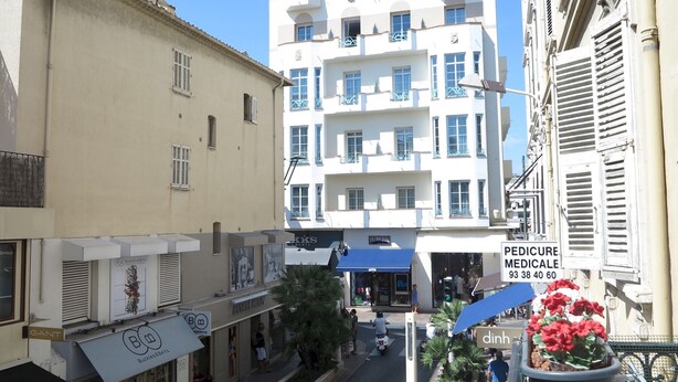 Vista d'un carrer amb un edifici amb la inscripció 'PEDICURE MEDICALE' i un cartell del 'MONDIA HOTEL'.
