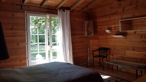 Ein Zimmer in einer Holzhütte mit einem Bett, einer Bank und einem Fenster mit Vorhängen.