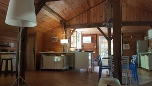 Ein rustikales Blockhaus-Interieur mit Küche, Essbereich und einem großen Fenster, das für natürliches Licht sorgt.