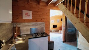 A kitchen with a gas stove, a sink, and cabinets. There is a wooden staircase leading to another room. - Cottages to Orient - Chalet Nature (Géraudot)
