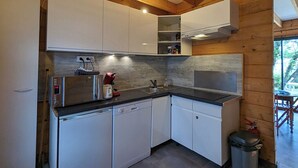 A compact kitchen with white cabinets, a microwave, a sink, and a dishwasher. - Cottages to Orient - Chalet Nature (Géraudot)